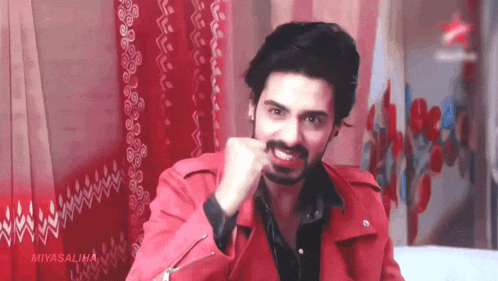 a man in a red jacket and black shirt is making a funny face .