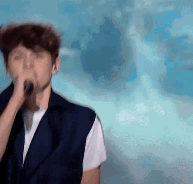 a man is singing into a microphone with a blue sky in the background