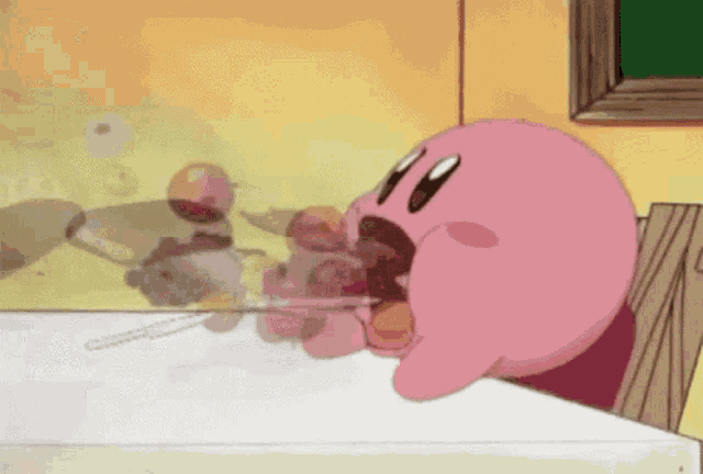 a pink cartoon character is sitting at a table with a spoon in its mouth .