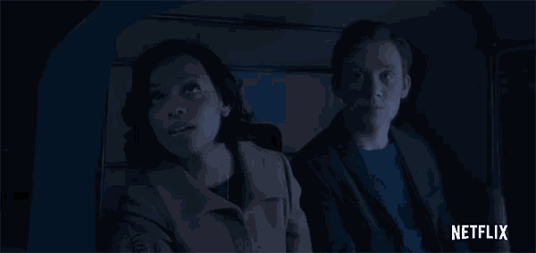 a man and a woman are sitting in a dark room with a netflix logo in the corner