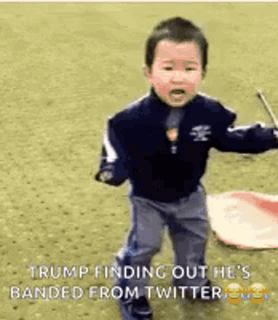 a little boy is standing on a field holding a drum .