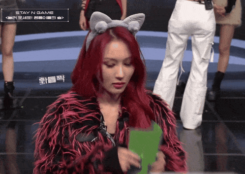 a woman with red hair is wearing a cat ear headband and a fur coat