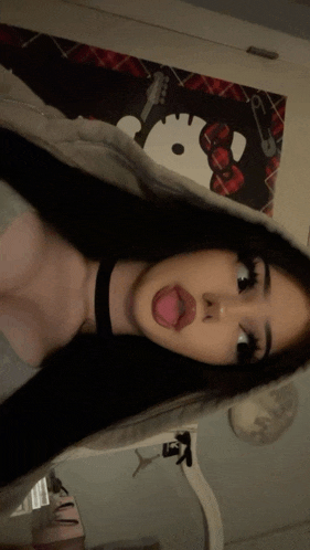 a girl is sticking her tongue out in front of a hello kitty wallpaper