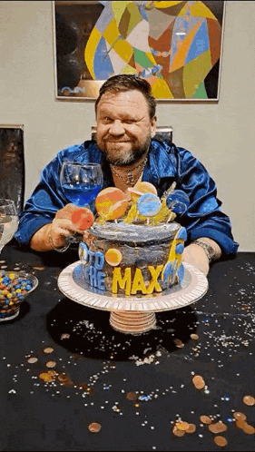 a man is sitting at a table holding a glass of wine in front of a birthday cake .