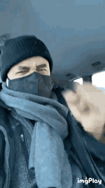 a man wearing a mask and a scarf is sitting in a car ..