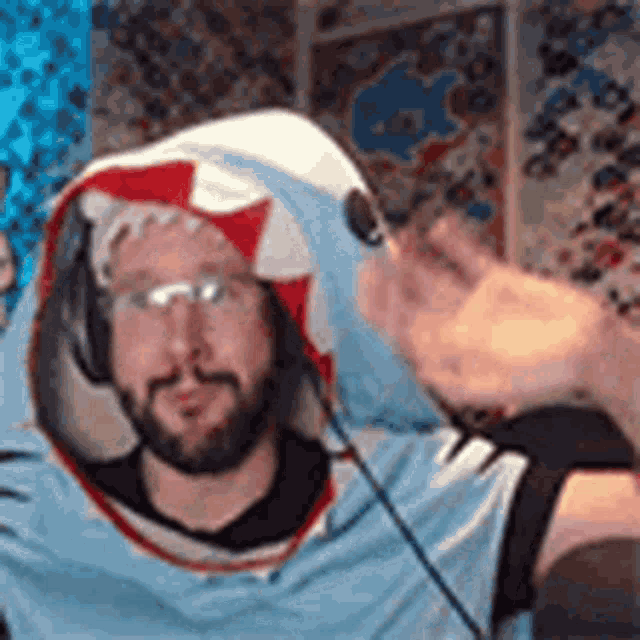 a man with a beard is wearing a shark costume and headphones while playing a video game .