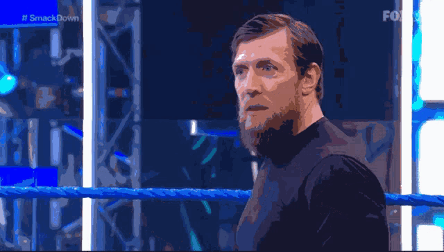 a man with a beard is standing in front of a smackdown sign