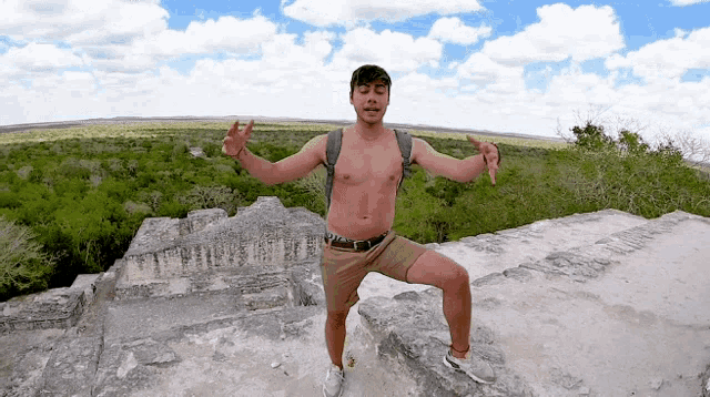 a man without a shirt is standing on top of a rocky hill
