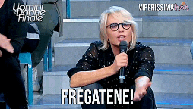 a woman with glasses is holding a microphone and saying fregatene