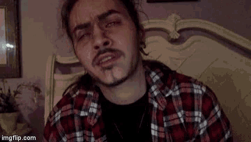 a man in a plaid shirt is making a funny face while sitting on a bed ..