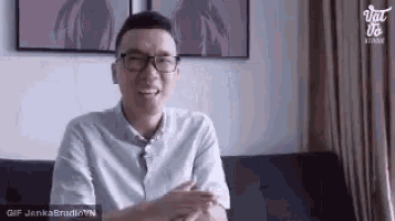 a man wearing glasses is sitting on a couch .