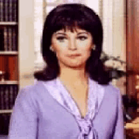 a woman in a purple shirt and tie is standing in front of a window .
