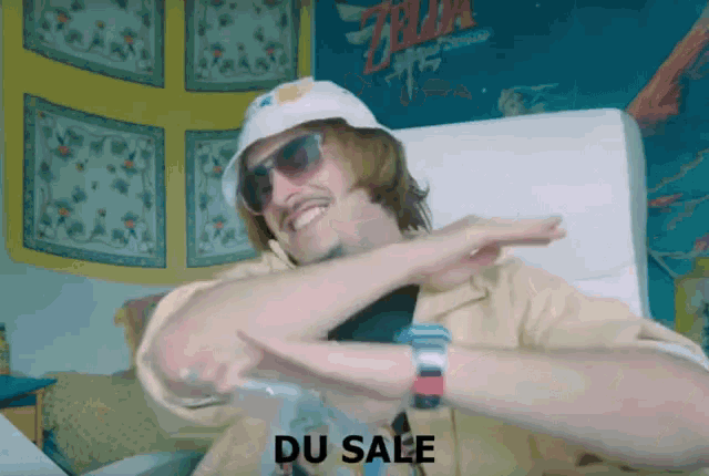 a man wearing a hat and sunglasses is sitting in a chair with the word du sale above him