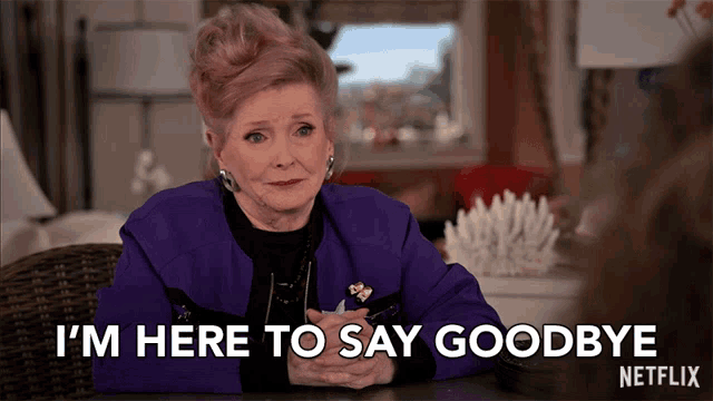 a woman is sitting at a table and says i 'm here to say goodbye