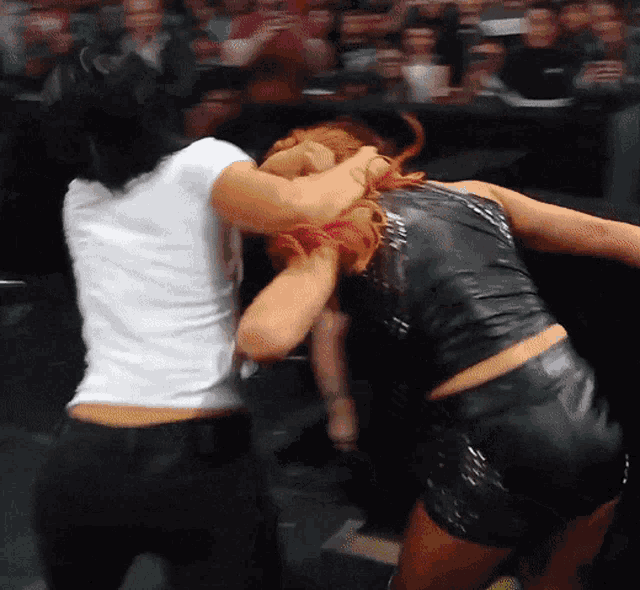a woman in a white shirt is fighting another woman in a black dress