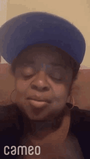 a woman is wearing a blue hat and earrings .