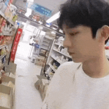 a young man in a white shirt is walking through a store .