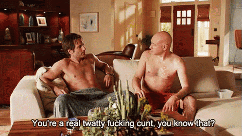 two shirtless men are sitting on a couch and talking to each other .