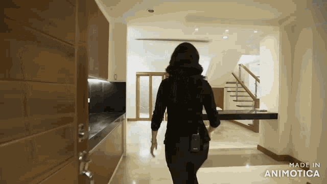 a woman walking through a room with the words made in animatica on the bottom right
