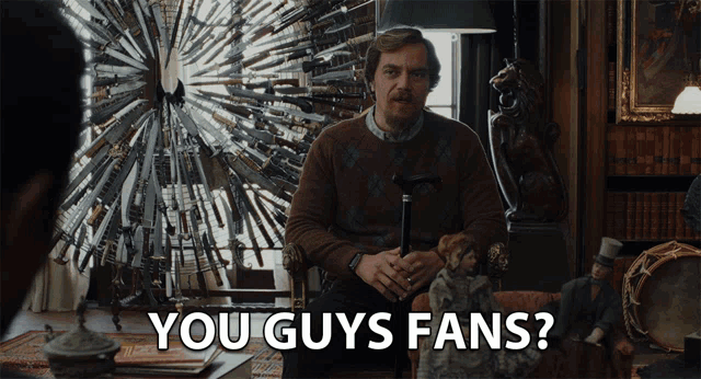 a man with a cane is sitting in front of a display of knives and says you guys fans