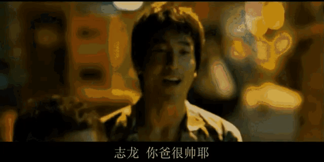 a man is smiling in front of a blurry background with chinese writing on it