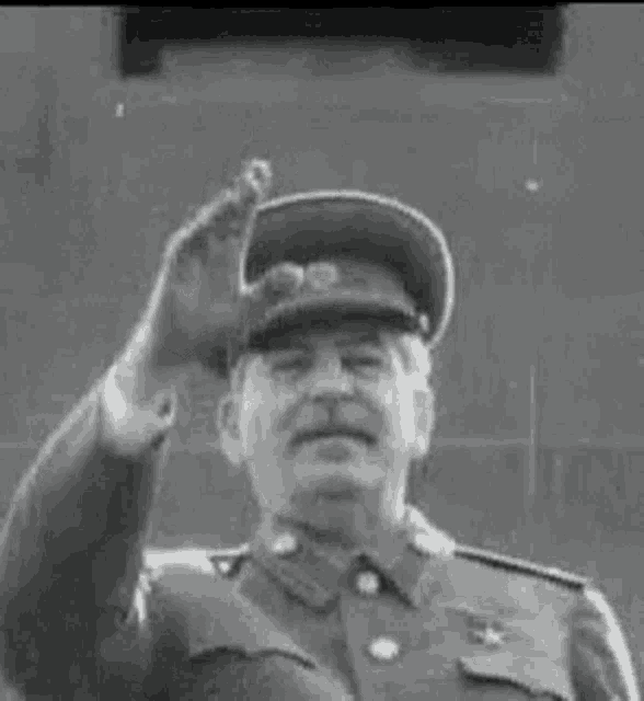 a black and white photo of a man in a military uniform giving a salute .