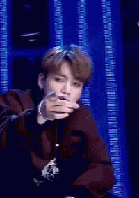 a young man in a suit is making a heart shape with his hands while wearing a microphone .