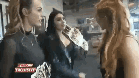 a group of women are standing next to each other in a room and talking .