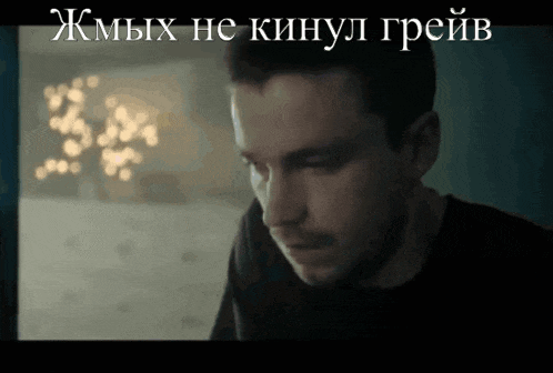 a close up of a man 's face in a dark room with a foreign language written above him