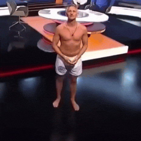 a shirtless man is standing in front of a table with a chair in the background
