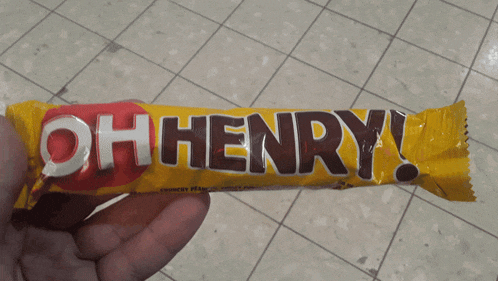 a person is holding a yellow oh henry bar