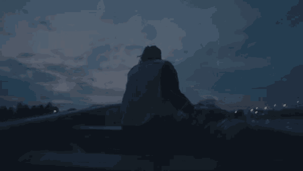 a man in a yellow vest is sitting on the back of a truck at night