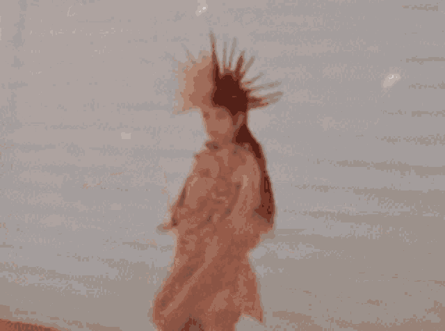 a woman with a mohawk on her head is wearing a pink dress and earrings .