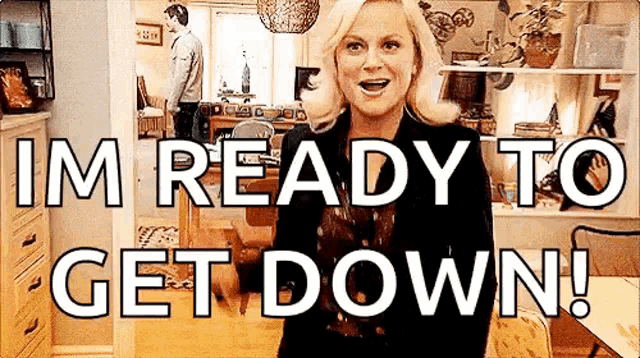 a woman is standing in a living room with the words `` im ready to get down '' written on the screen .