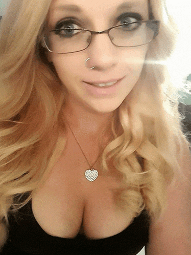 a blonde woman wearing glasses and a heart shaped necklace