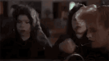 two women are sitting next to each other in a church . one of the women is wearing a black veil .