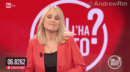 a woman in a red jacket is standing in front of a sign that says l' ha visto