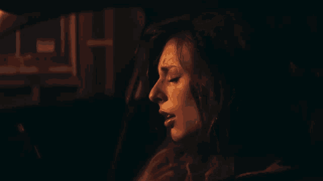 a woman is sitting in a dark car with her eyes closed