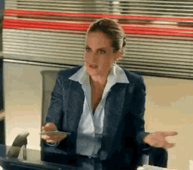 a woman in a suit is sitting at a desk with a computer .