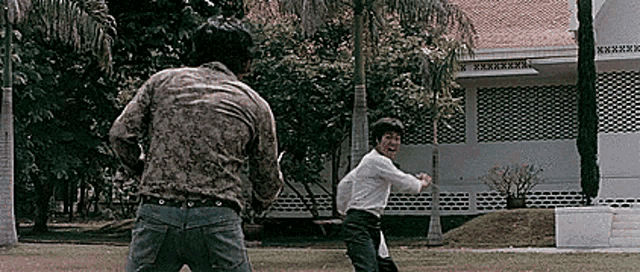 two men are playing a game of cricket in a park .