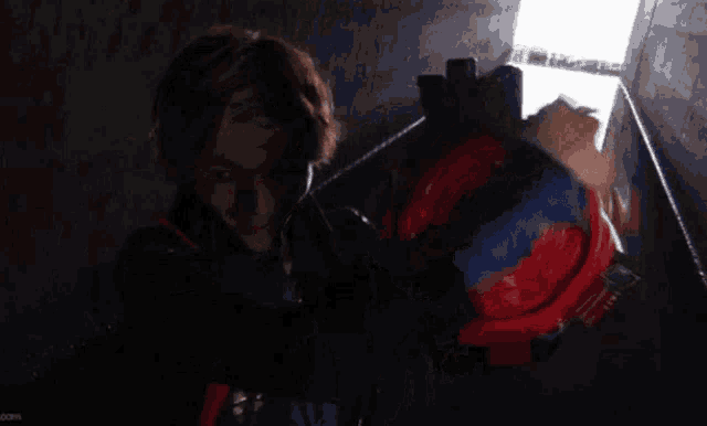 a man in a black jacket is holding a red object with a hand on it