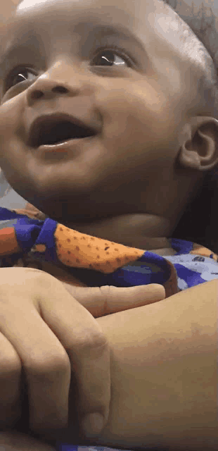 a close up of a baby 's face with a blue shirt on