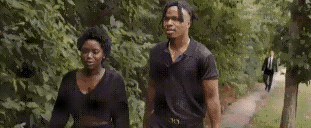 a man and a woman are walking down a path in a forest .