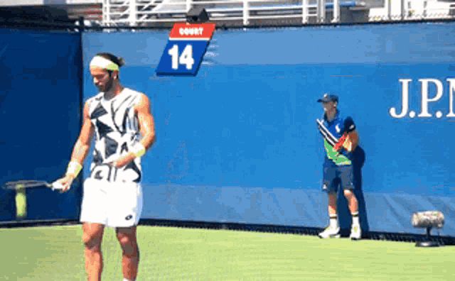 a man playing tennis in front of a wall with the number 14 on it