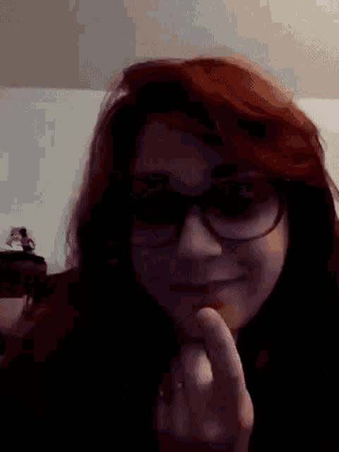 a woman with red hair is wearing glasses and making a face .