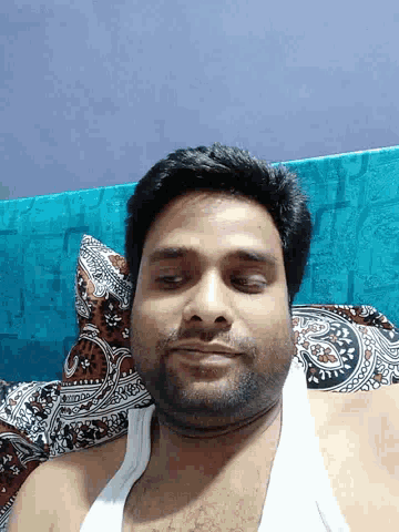 a man in a white tank top is laying on a blue couch