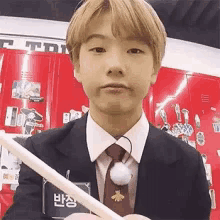 a young man in a suit and tie is holding a straw in his hand .