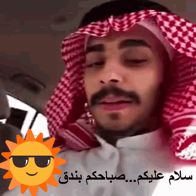 a man wearing a red and white head scarf and sunglasses with arabic writing