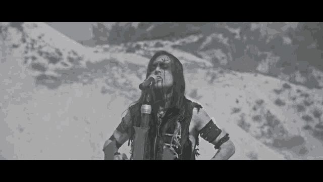 a man with long hair is singing into a microphone in the snow .