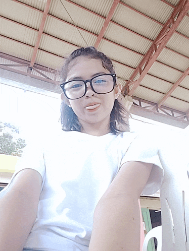 a girl wearing glasses and a white shirt is smiling for the camera